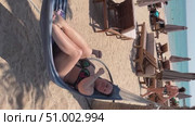 A 50-year-old woman on the beach in Doha is riding a hammock. Стоковое видео, видеограф IRYNA ZAKHARANKA / Фотобанк Лори