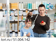 Woman chooses remedy for treating itchy scalp in child. Стоковое фото, фотограф Яков Филимонов / Фотобанк Лори