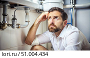 Worried Man Underneath A Leaky Sink Needs a Plumber. Generative AI. Стоковое AI-изображение, AI-художник Roman Zavorotny / Фотобанк Лори