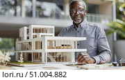 An architect showcases a detailed building model in a bright, modern workspace, highlighting innovative design and creative techniques in architecture. Стоковое AI-видео, аниматор Данила Большаков / Фотобанк Лори