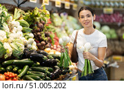 Girl client near vegetable stand in store choose bunch of green onion. Стоковое фото, фотограф Яков Филимонов / Фотобанк Лори