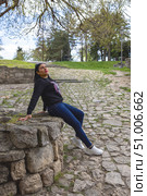 A young woman relaxes on a rock wall in a scenic park with a cobblestone path. Стоковое фото, фотограф Виктор Ветошкин / Фотобанк Лори