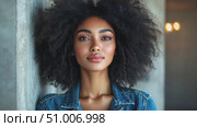 A young woman showcases her natural curls while leaning against a concrete wall, embodying confidence in a stylish outfit. Стоковое AI-видео, аниматор Данила Большаков / Фотобанк Лори