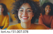 A confident young woman with curly hair and glasses engages in a thoughtful discussion with her peers in a cozy environment. Стоковое AI-видео, аниматор Данила Большаков / Фотобанк Лори