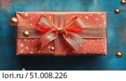A beautifully wrapped present in vibrant orange with a shimmering ribbon sits on a textured blue surface, creating a festive atmosphere. Стоковое AI-видео, аниматор Данила Большаков / Фотобанк Лори