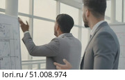 Businessmen discussing charts during meeting in bright office space. Стоковое AI-видео, аниматор Александра Рублева / Фотобанк Лори