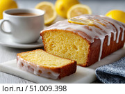 Homemade lemon drizzle cake with icing. Classic lemon pound cake with citrus glaze and zest. Whole loaf, side view, close up. Fresh homemade baked dessert with lemon slices. Blurred tea set background. Стоковое AI-изображение, AI-художник Марина Демидюк / Фотобанк Лори