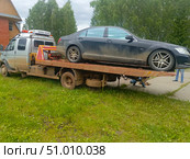 A muddy Mercedes-Benz sedan on a flatbed tow truck in a realistic style in gray and black colors representing vehicle towing service and accident assistance. Стоковое фото, фотограф Елена Высокова / Фотобанк Лори