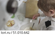 Young boy adding sugar to oatmeal with sliced apples in kitchen. Стоковое видео, видеограф Константин Шишкин / Фотобанк Лори