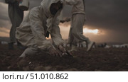 Person planting flowers in dark field during stormy skies at dusk. Стоковое AI-видео, аниматор Сергей Толмачёв / Фотобанк Лори
