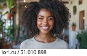 A woman with curly hair beams with joy in a lively setting filled with plants and natural light, radiating warmth and positivity. Стоковое AI-видео, аниматор Данила Большаков / Фотобанк Лори