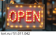 Flashing light label Open on door of bar or cafe. Sign on window of pub in big city in evening or at night. Wooden sign with glowing letters. Стоковое AI-видео, аниматор Ирина / Фотобанк Лори