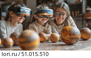 Three young girls immerse themselves in an exciting virtual reality experience, exploring planets while sitting indoors during a sunny day. Стоковое AI-видео, аниматор Данила Большаков / Фотобанк Лори