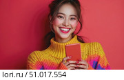 A young woman beams with joy while holding her smartphone, showcasing her vibrant personality against a bright orange backdrop. Стоковое AI-видео, аниматор Данила Большаков / Фотобанк Лори