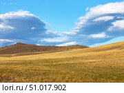 Unusual stratocumulus clouds over the steppe meadows and hills of Olkhon Island on the shore of Lake Baikal early in the summer morning. Beautiful landscape. Natural background. Summer travels. Стоковое фото, фотограф Виктория Катьянова / Фотобанк Лори