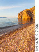 Beautiful sunset landscape of Baikal Lake. View of pebble beach of Small Sea and rocky coast of Olkhon Island on quiet August evening. Picturesque seascape. Natural background. Summer travels. Стоковое фото, фотограф Виктория Катьянова / Фотобанк Лори