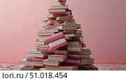 A striking arrangement features a pyramid of stacked books in varying colors on a decorative surface, emphasizing creativity and design. Стоковое AI-видео, аниматор Данила Большаков / Фотобанк Лори