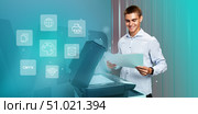 Young man operating a multifunction printer in a modern office and reviewing printed documents with satisfaction. Стоковое фото, фотограф Сергей Толмачёв / Фотобанк Лори