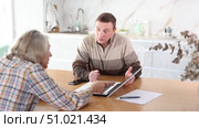 Male agent showing presentation and making offer to old woman. Old woman considering offer from agent. Стоковое видео, видеограф Яков Филимонов / Фотобанк Лори