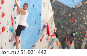Sporty man grabbing ledges of artificial climbing wall in bouldering centre. Стоковое видео, видеограф Яков Филимонов / Фотобанк Лори