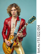 A Seductive Rocker Guy Playing Guitar Against a Blue Background. Generative AI. Стоковое AI-изображение, AI-художник Roman Zavorotny / Фотобанк Лори
