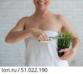 Unrecognizable woman shears a potted plant with scissors. Axillary depilation. Smiling girl removes unwanted vegetation on the body. Armpit epilation concept. Стоковое фото, фотограф Михаил Решетников / Фотобанк Лори