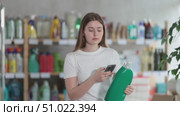 Girl buyer scans qr code on liquid powder label. Стоковое видео, видеограф Яков Филимонов / Фотобанк Лори