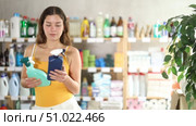 Girl view trademark sign on label, pick eco friendly, tile cleaner, other client shopping behind. Стоковое видео, видеограф Яков Филимонов / Фотобанк Лори