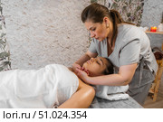 A woman is getting a neck massage while lying on a table. Spa, health and relaxation concept. Стоковое фото, фотограф Владислав Тригуб / Фотобанк Лори