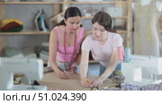 Manager of a sewing workshop teaches a young girl seamstress to draw using patterns. Стоковое видео, видеограф Яков Филимонов / Фотобанк Лори