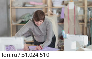 Woman seamstress cuts fabric on cutting table. Стоковое видео, видеограф Яков Филимонов / Фотобанк Лори