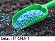 Green scoop with fertilizer blue granules. Granular chemical fertiliser for plant over soil background. Role of nutrients mineral in plants growth, soil life. Space for text. Gardening time. Planting. Стоковое AI-изображение, AI-художник Марина Демидюк / Фотобанк Лори
