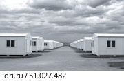 Rows of prefabricated houses under cloudy sky forming a refugee camp. Стоковое AI-изображение, AI-художник Юрий Поздников / Фотобанк Лори