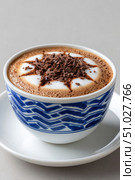 Mocha coffee with chocolate shavings and latte art in a blue and white cup. Стоковое AI-изображение, AI-художник Юрий Поздников / Фотобанк Лори