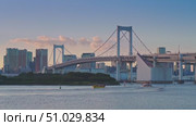Tokyo, Japan - Oct 13 2024, 4k, panoramic view of Tokyo Bay with a cable-stayed Rainbow Bridge above it, a boat and a water bus sailing, at sunset, Tokyo, Japan. Редакционное видео, видеограф Сергей Богомяко / Фотобанк Лори