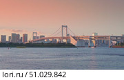Tokyo, Japan - Oct 13 2024, 4k, panoramic view of Tokyo Bay with a cable-stayed Rainbow Bridge above it, a boat and a water bus sailing, at sunset, Tokyo, Japan. Редакционное видео, видеограф Сергей Богомяко / Фотобанк Лори
