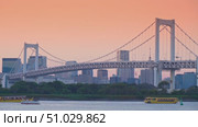 Tokyo, Japan - Oct 13 2024, 4k, panoramic view of Tokyo Bay with a cable-stayed Rainbow Bridge above it, a boat and a water bus sailing, at sunset, Tokyo, Japan. Редакционное видео, видеограф Сергей Богомяко / Фотобанк Лори