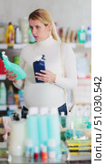 Focused pregnant woman choosing safe and eco-friendly products for household cleaning, comparing different glass cleaner sprays with interest while shopping in supermarket. Стоковое видео, видеограф Яков Филимонов / Фотобанк Лори