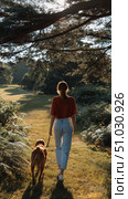 Woman strolls through a sunlit park with her golden retriever, enjoying the serenity of nature during a warm afternoon. Стоковое AI-изображение, AI-художник Сергей Толмачёв / Фотобанк Лори