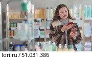 Checking expiration date of liquid hand soap - female shopper in winter clothes scans QR code on label of liquid hand soap using her smartphone. Стоковое видео, видеограф Яков Филимонов / Фотобанк Лори