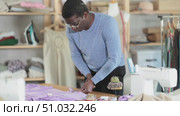 African man seamstress cuts fabric on cutting table. Craftsman creates blanks from linen for future product. Individual production of fashionable clothes, unique handmade products. Стоковое видео, видеограф Яков Филимонов / Фотобанк Лори
