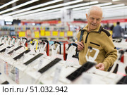 elderly man examines smart watch in showroom of electronics store. Стоковое фото, фотограф Татьяна Яцевич / Фотобанк Лори