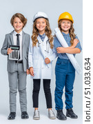 Three children dressed as professionals, one with a calculator, another in a hard hat and goggles, and the last holding blueprints, showcasing future career aspirations and teamwork. Стоковое AI-изображение, AI-художник Ирина Ручушкина / Фотобанк Лори