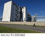 Мужчина едет на самокате на фоне хлебного элеватора. Редакционное фото, фотограф Жилина Людмила / Фотобанк Лори