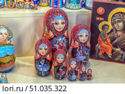A set of painted Russian nesting dolls with images of ballerinas and ballet scenes, decorated with bright ornaments and rhinestones. Each doll has a unique painting, reflecting the traditions of Russian folk art and the sophistication of ballet culture. In the background, other souvenirs are visible, including an icon and painted dolls. Стоковое фото, фотограф Анна Кривицкая / Фотобанк Лори