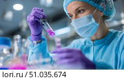 Scientist conducts experiment in laboratory with vibrant substances and glassware in modern research facility. Стоковое AI-изображение, AI-художник Сергей Толмачёв / Фотобанк Лори