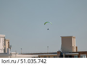 Paraglider mid-flight against clear blue sky in city. Стоковое фото, фотограф Екатерина Якименко / Фотобанк Лори