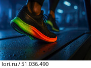 Athlete sprints on wet treadmill wearing black running shoe with vibrant neon rainbow sole, capturing dynamic fitness energy in dark gym. Стоковое AI-изображение, AI-художник Павел Муравьев / Фотобанк Лори