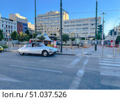 A classic white car is on a city street in front of modern and neoclassical buildings (2023 год). Редакционное фото, фотограф Виктор Ветошкин / Фотобанк Лори