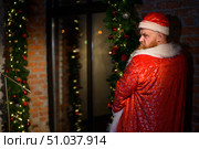 A humorous image of a man in a suit of Santa Claus pissing. View from the back Bad Santa Claus urinates in the room. vulgar humor. Стоковое фото, фотограф Михаил Решетников / Фотобанк Лори